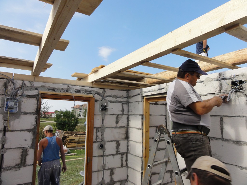 A Romanian electrician installs wiring in the larger house