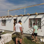 The roof structure starts to go up on the larger house
